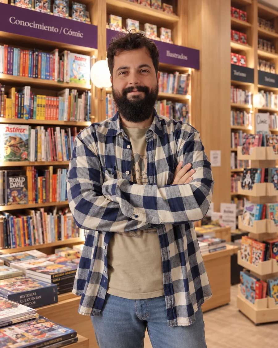 Víctor Corrales, con camisa de cuadros, entre estanterías.